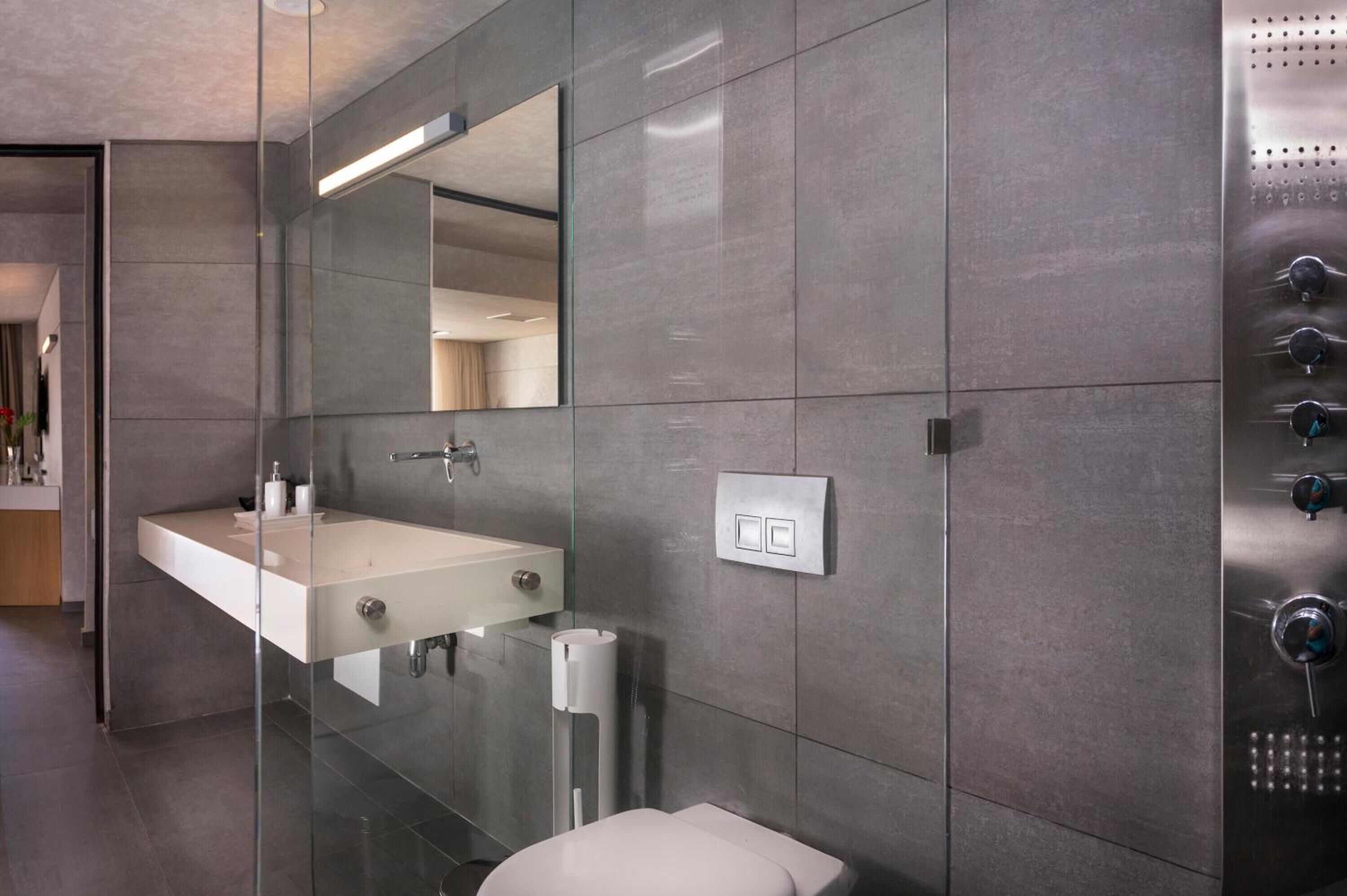 A modern bathroom with a glass-enclosed shower, a white sink, and a toilet.