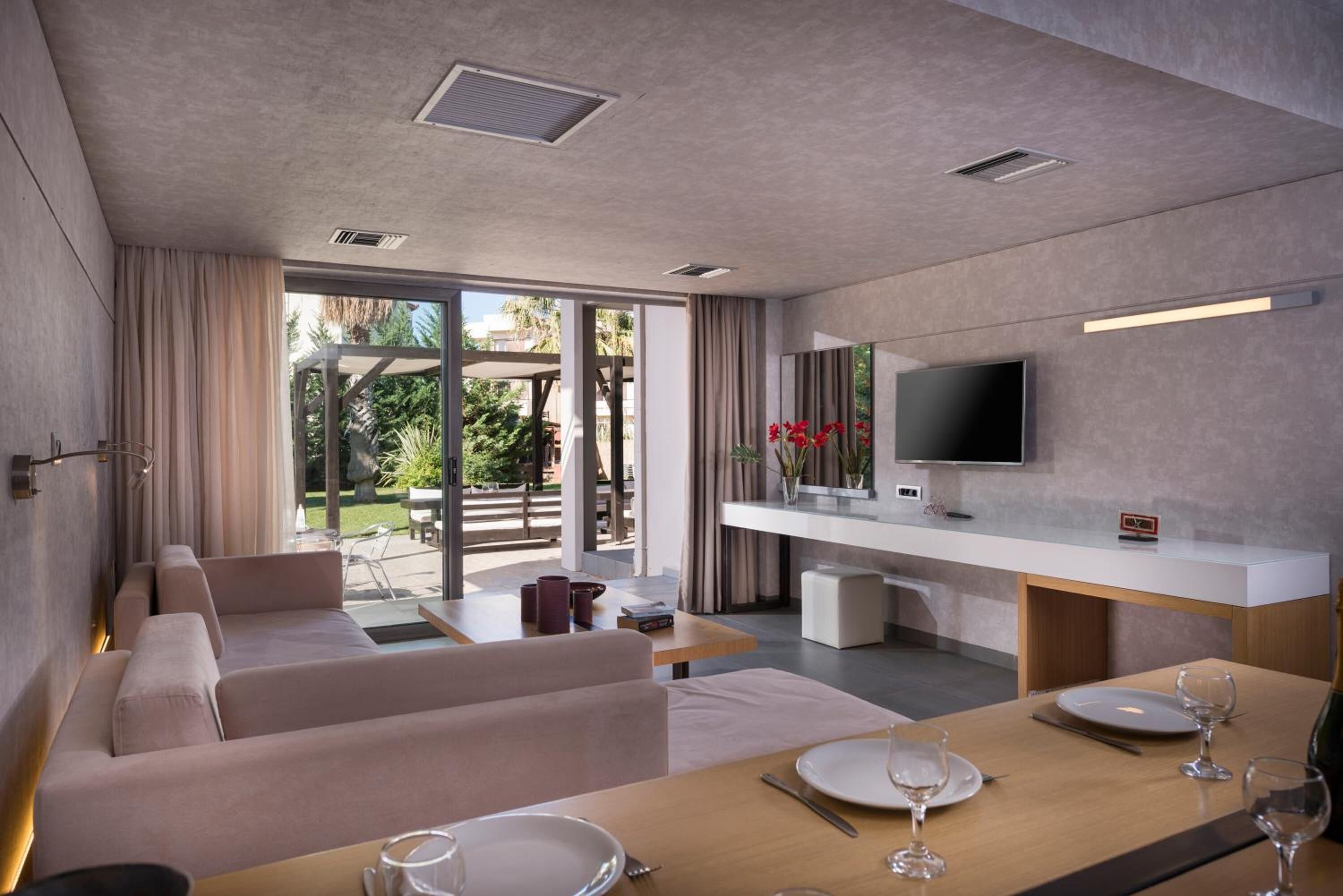 Un salon moderne avec un canapé, une table à manger pour deux personnes et un téléviseur fixé au mur.
