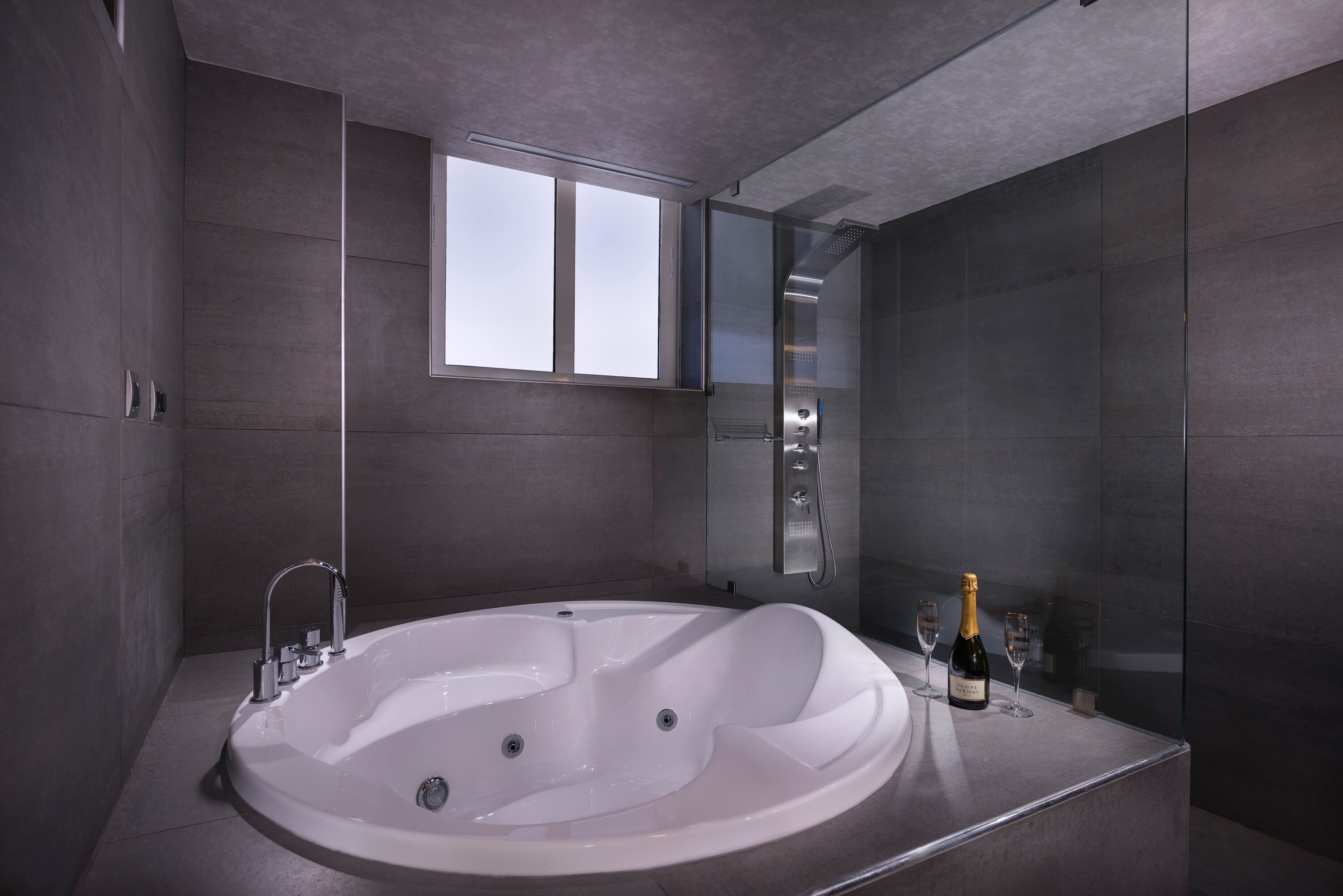 A modern bathroom with a large freestanding bathtub, a glass shower enclosure, and a large mirror.
