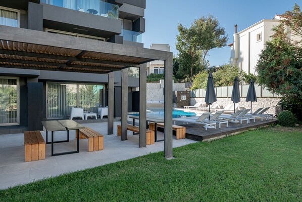 A modern outdoor pool area with lounge chairs and a covered seating area.
