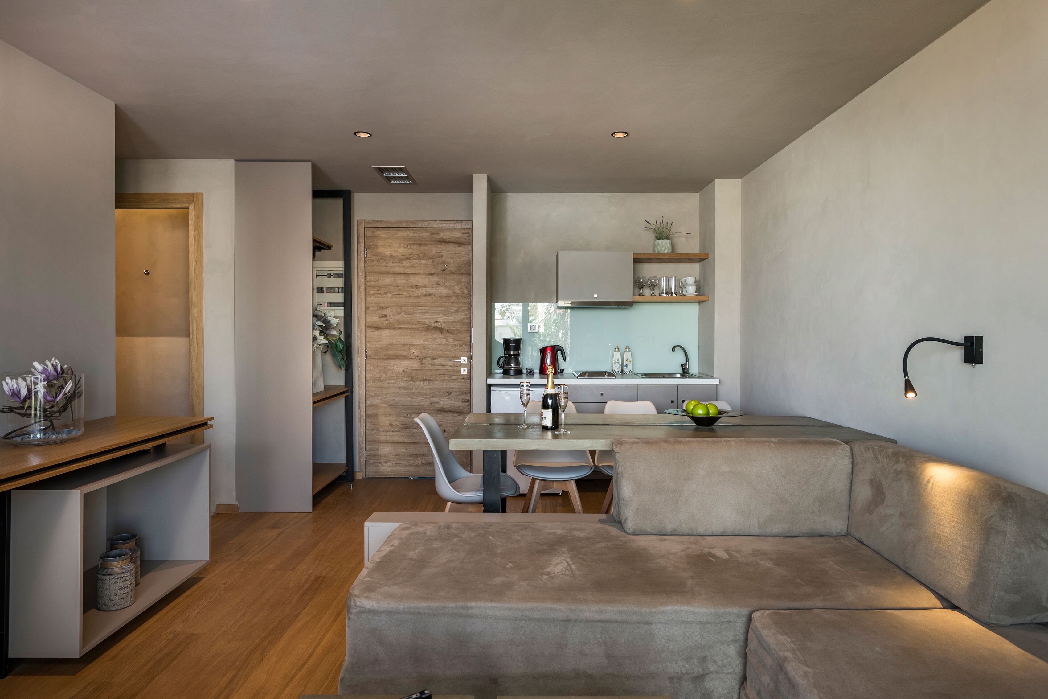 A modern living room with a sofa, a dining table with chairs, and a kitchen area in the background.