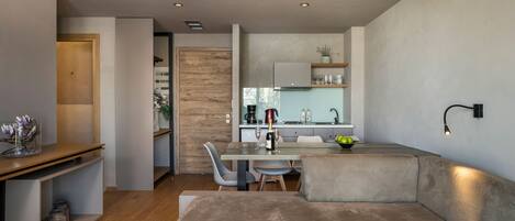 A modern living room with a sofa, a dining table with chairs, and a kitchen area in the background.