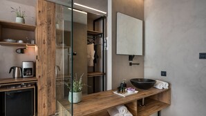 Uma casa de banho moderna com toucador de madeira, um espelho grande e uma máquina de café integrada.