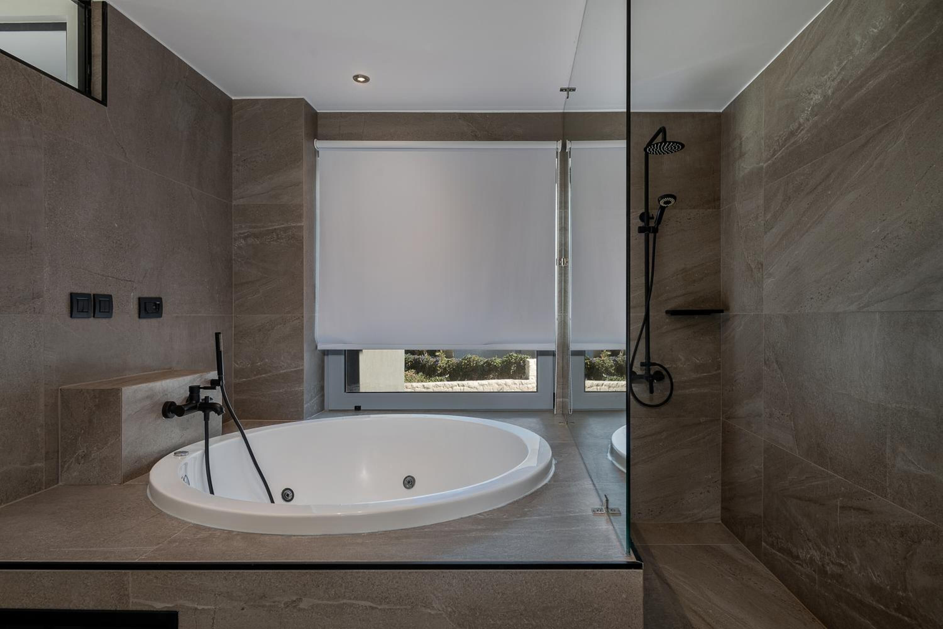 A modern bathroom with a large bathtub, a shower, and a window with a view.