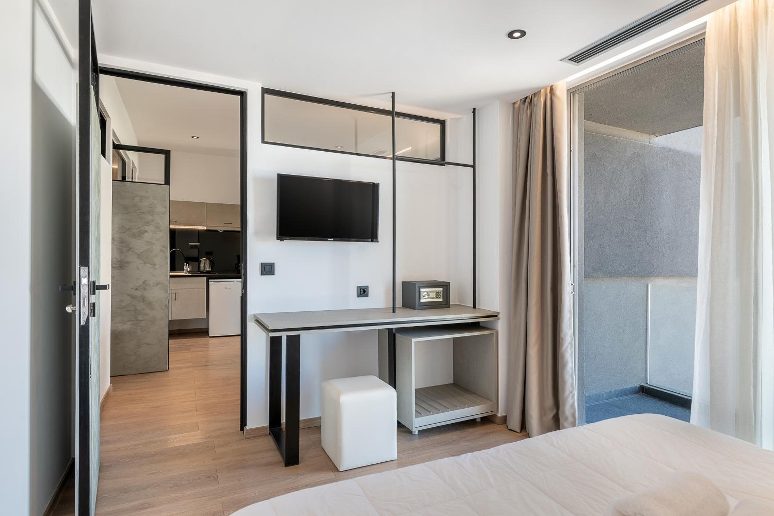 Quarto de hotel moderno com cama, escrivaninha, televisão e vista para o exterior.