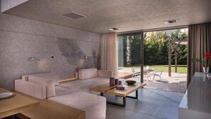 Uma sala de estar moderna com sofá, mesa de centro e vista para o exterior.