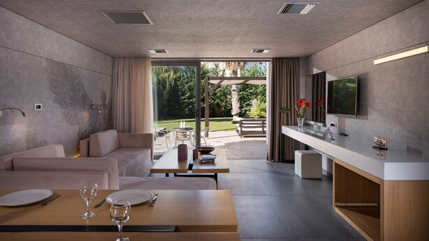 Uma sala de estar moderna com um sofá, mesa de jantar e uma TV fixada na parede.