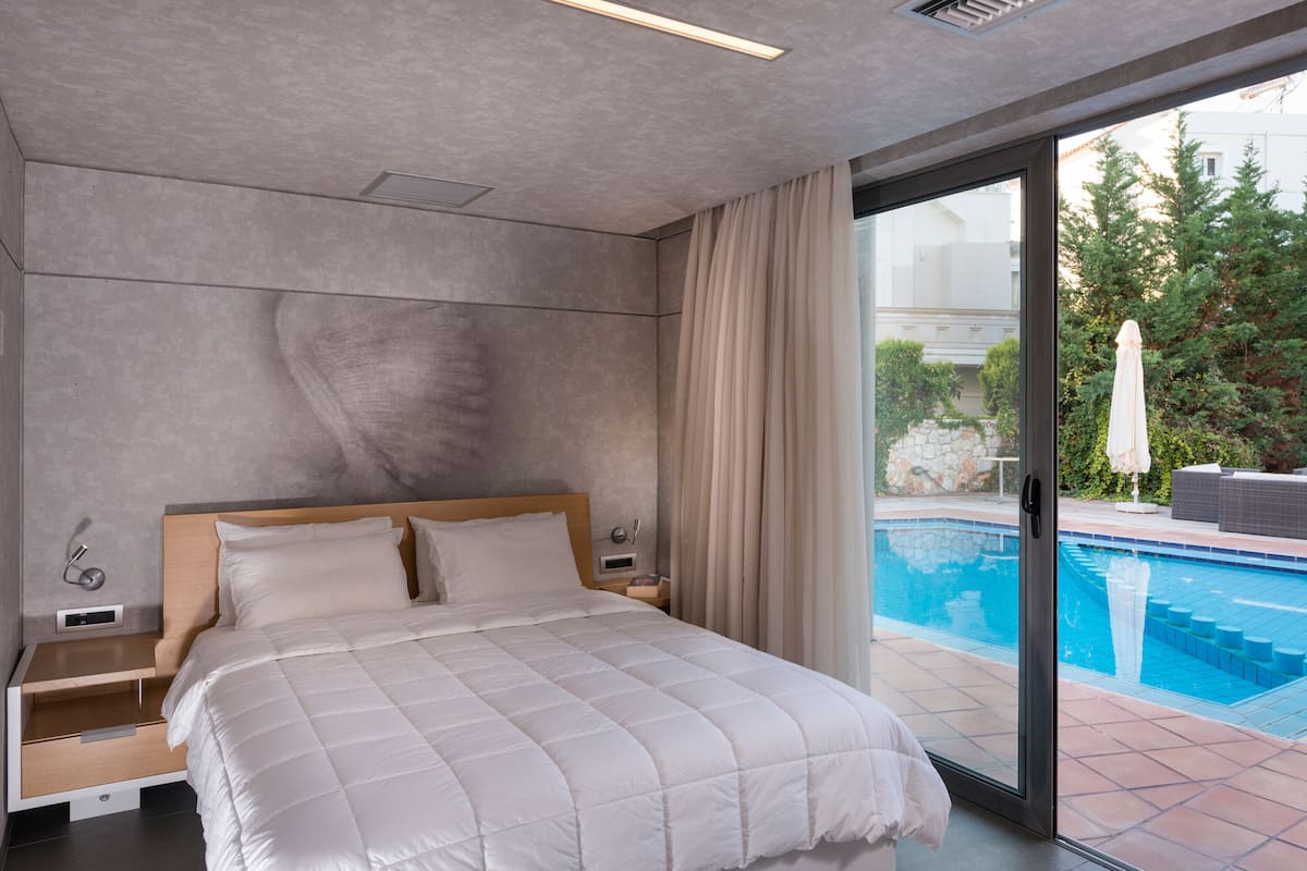 Un dormitorio moderno con una cama grande, una mesita de noche y vistas a una piscina.
