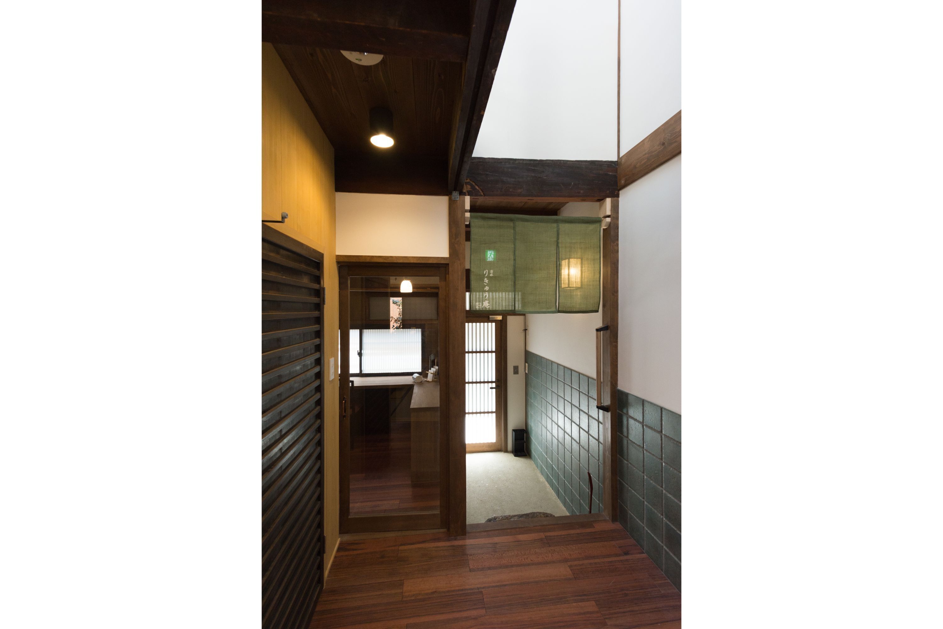 Un couloir étroit avec un plancher en bois et un mur recouvert de carreaux.