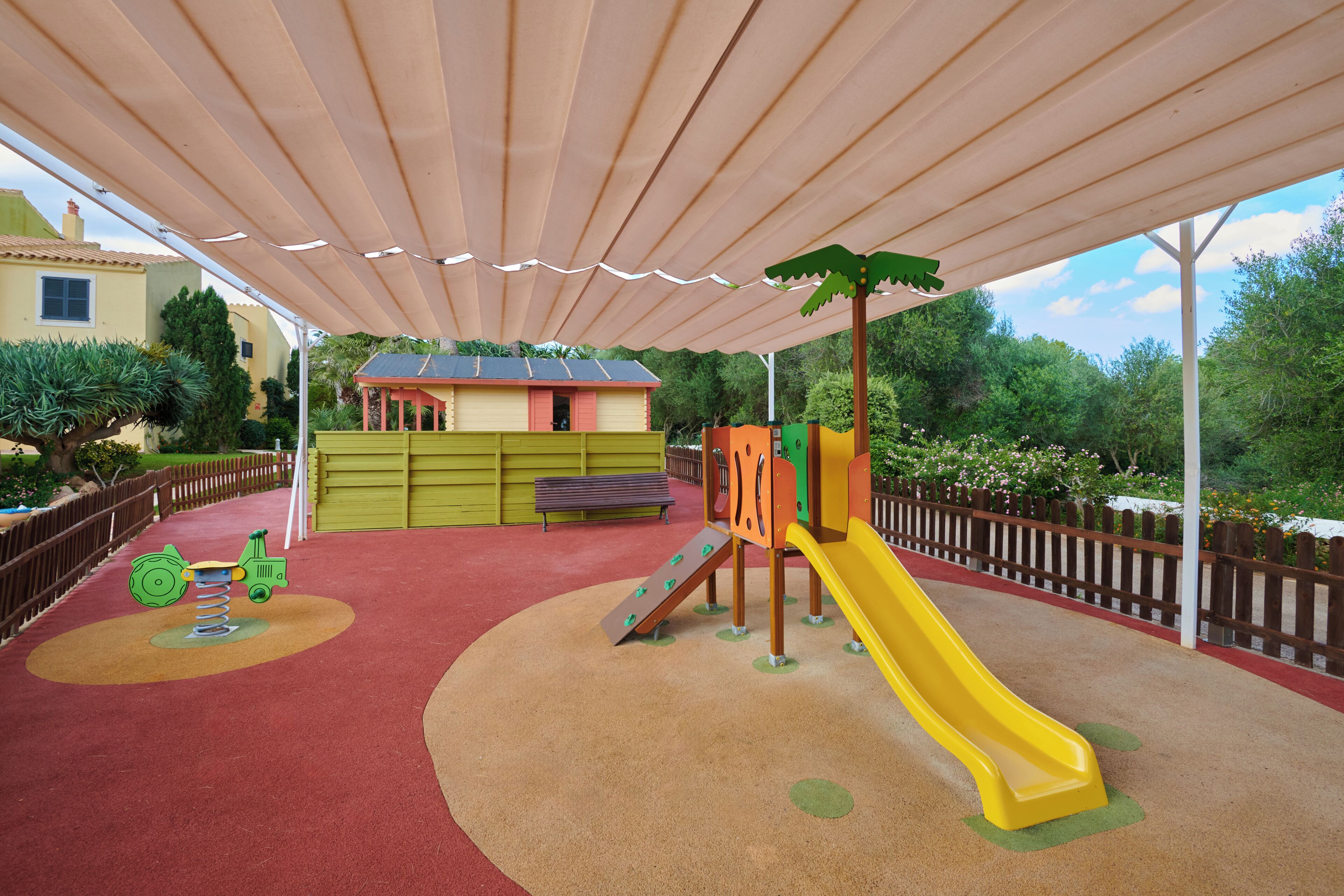 A playground with a slide, climbing structures, and a covered area.