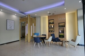 A modern waiting area with a reception desk, seating, and a wall-mounted bookshelf. - Hanting Hotel (Hangzhou)