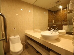 A bathroom with a toilet, bidet, and two sinks with mirrors. - Hanting Hotel (Hangzhou)