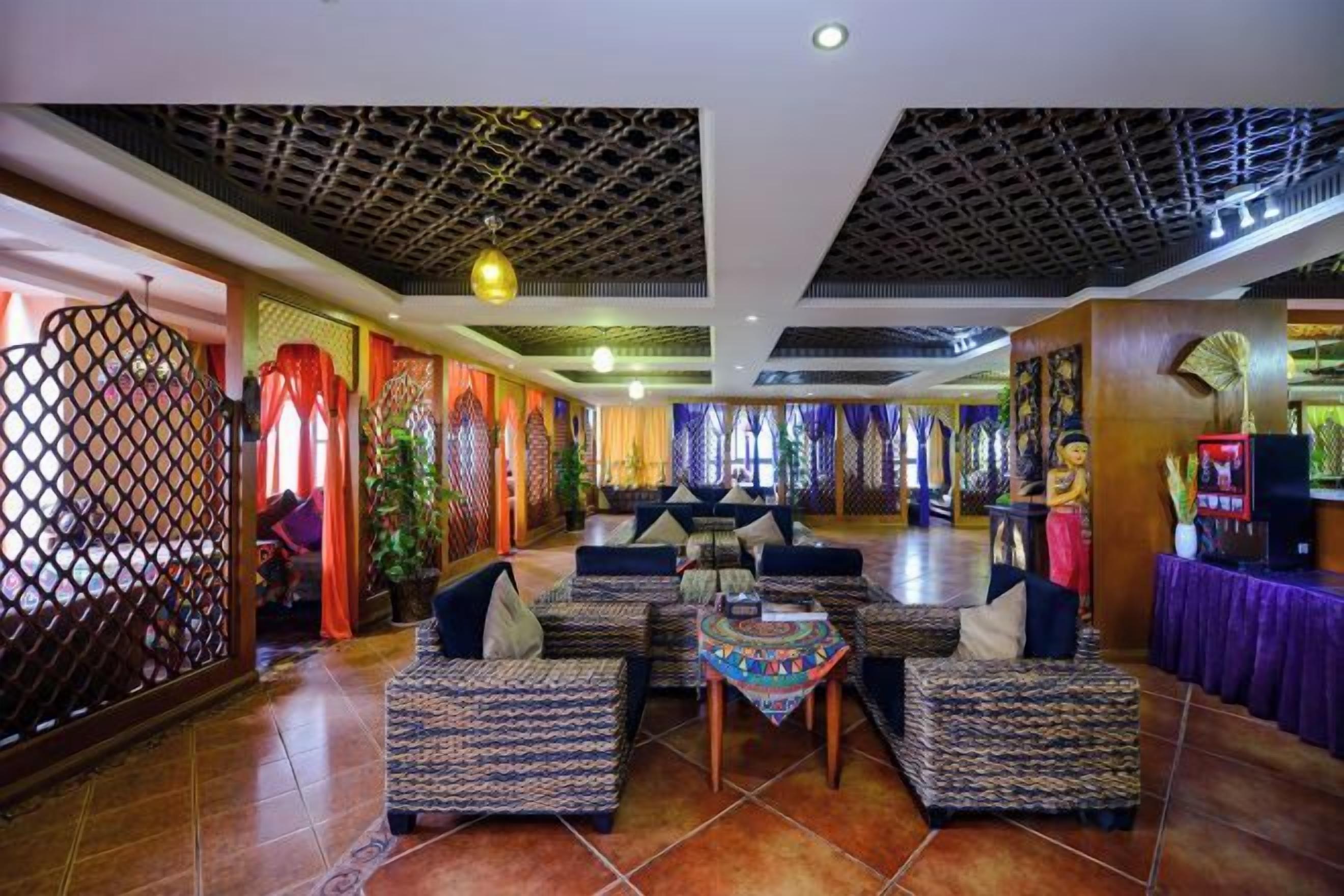 Un hall de hotel con sofás estampados, una mesa central y un techo decorativo.