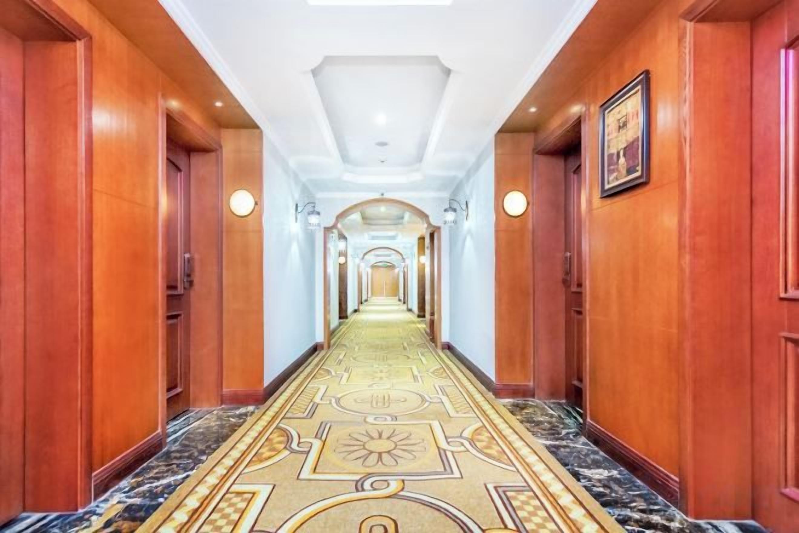 Un pasillo largo y estrecho con paredes de madera y una alfombra estampada.