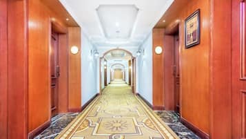 Un pasillo largo y estrecho con paredes de madera y una alfombra estampada.