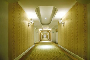 Passadís d'hotel amb paper tapet motllejat, aplics de paret i terra amb moqueta.