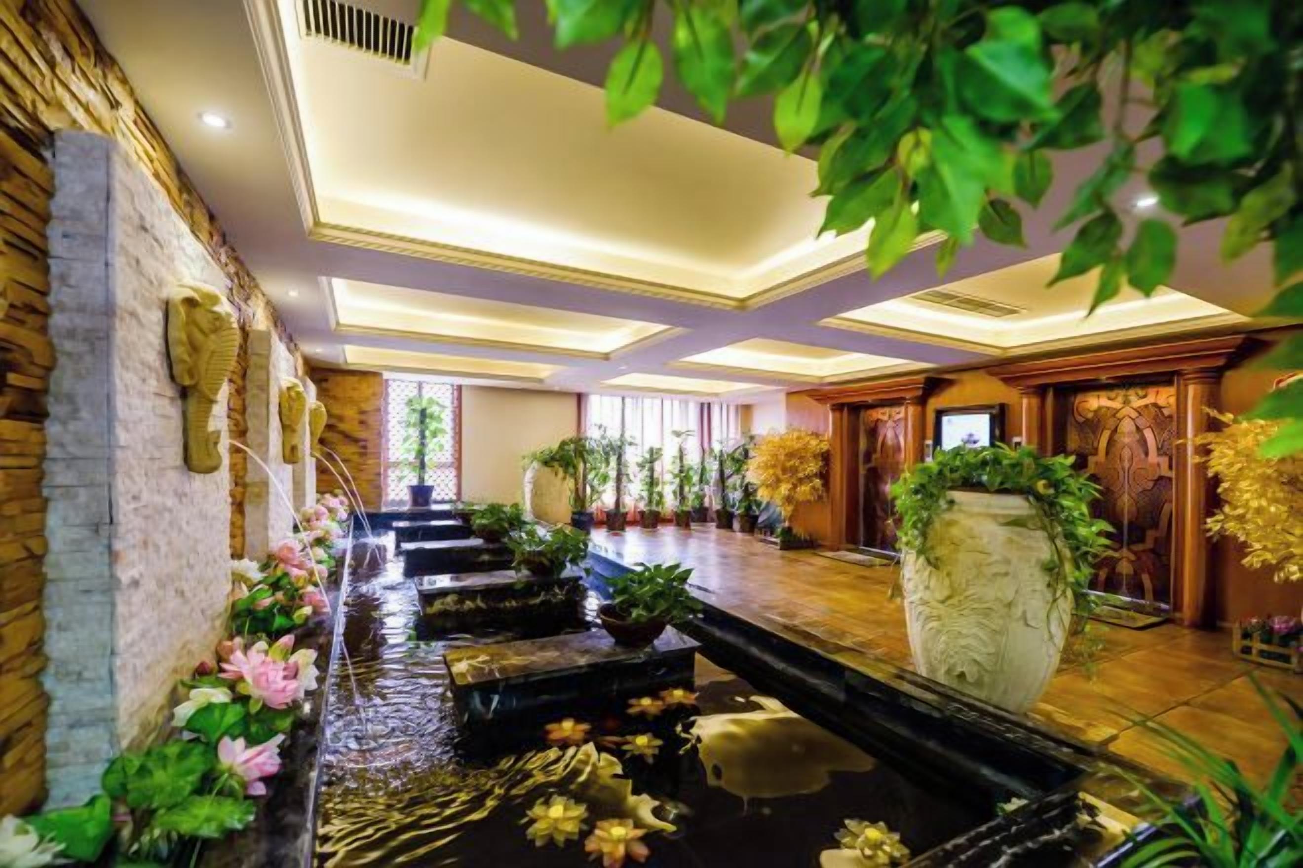 A hotel lobby with a water feature, stone walls, and indoor plants.