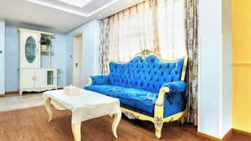 Una habitación con un sofá azul, una mesa blanca y un armario.