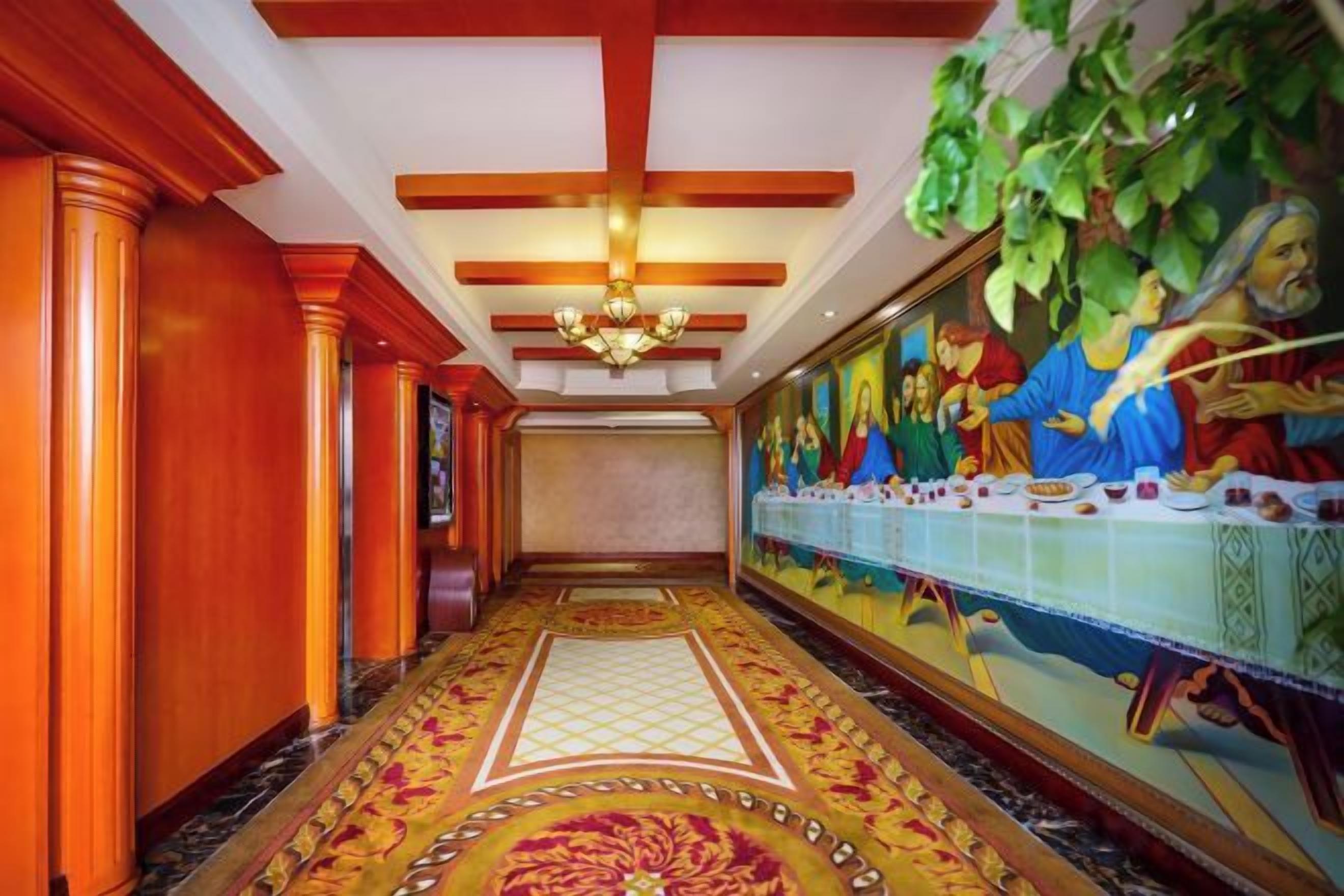 A hallway with a long mural, wooden paneling, and a patterned carpet.