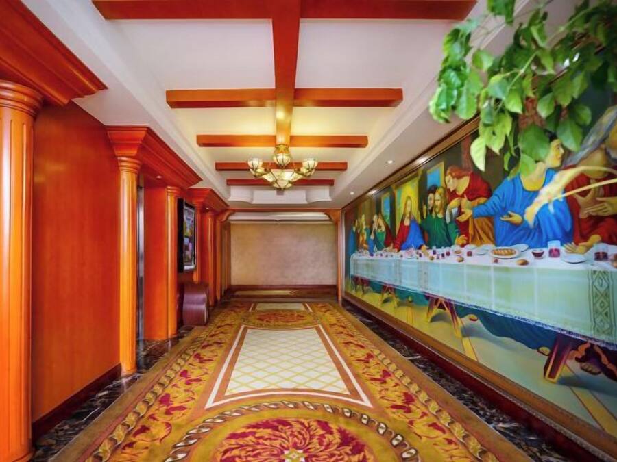 A hallway with a long mural, wooden paneling, and a patterned carpet.