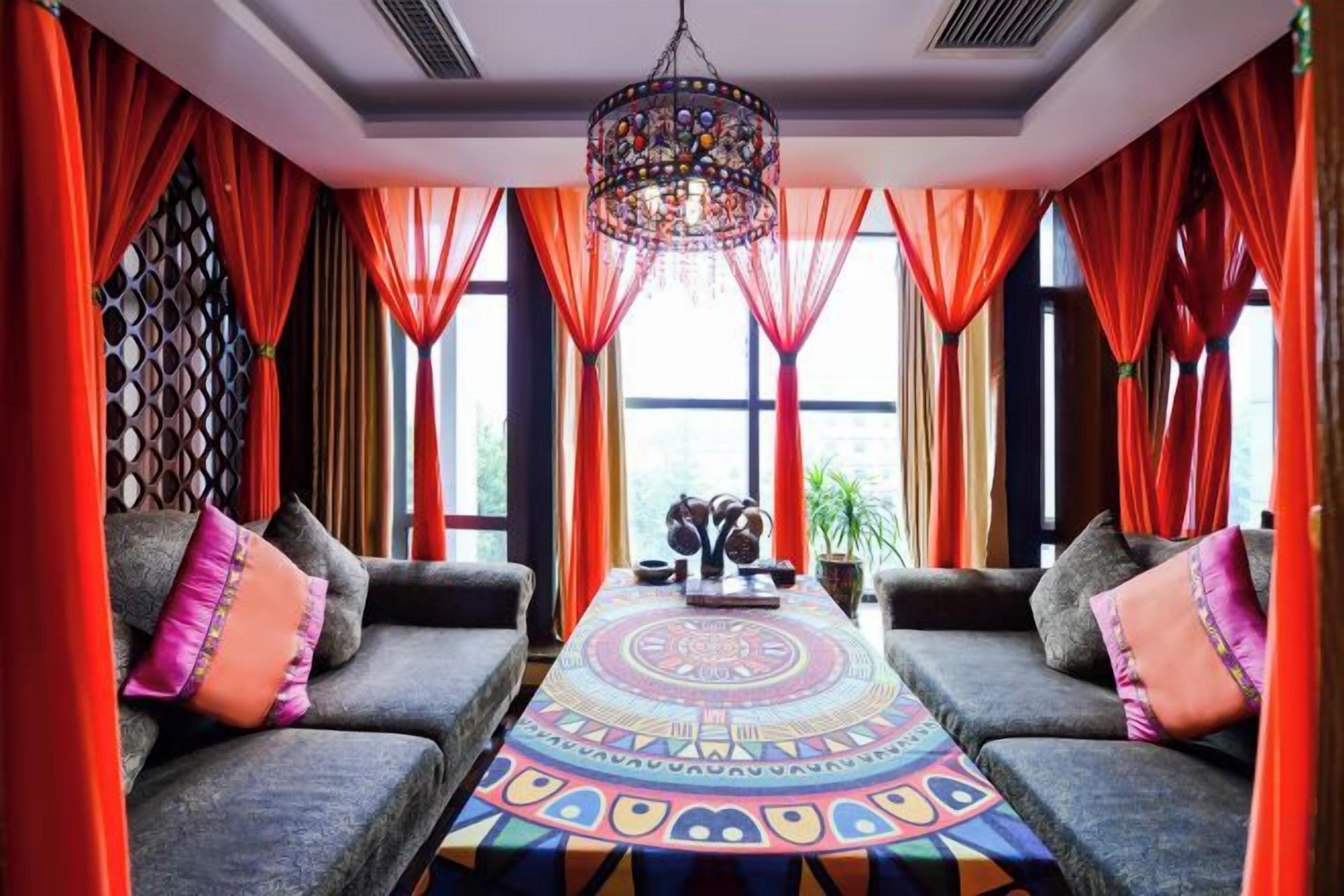 A room with a sofa set, a patterned rug, and a chandelier.