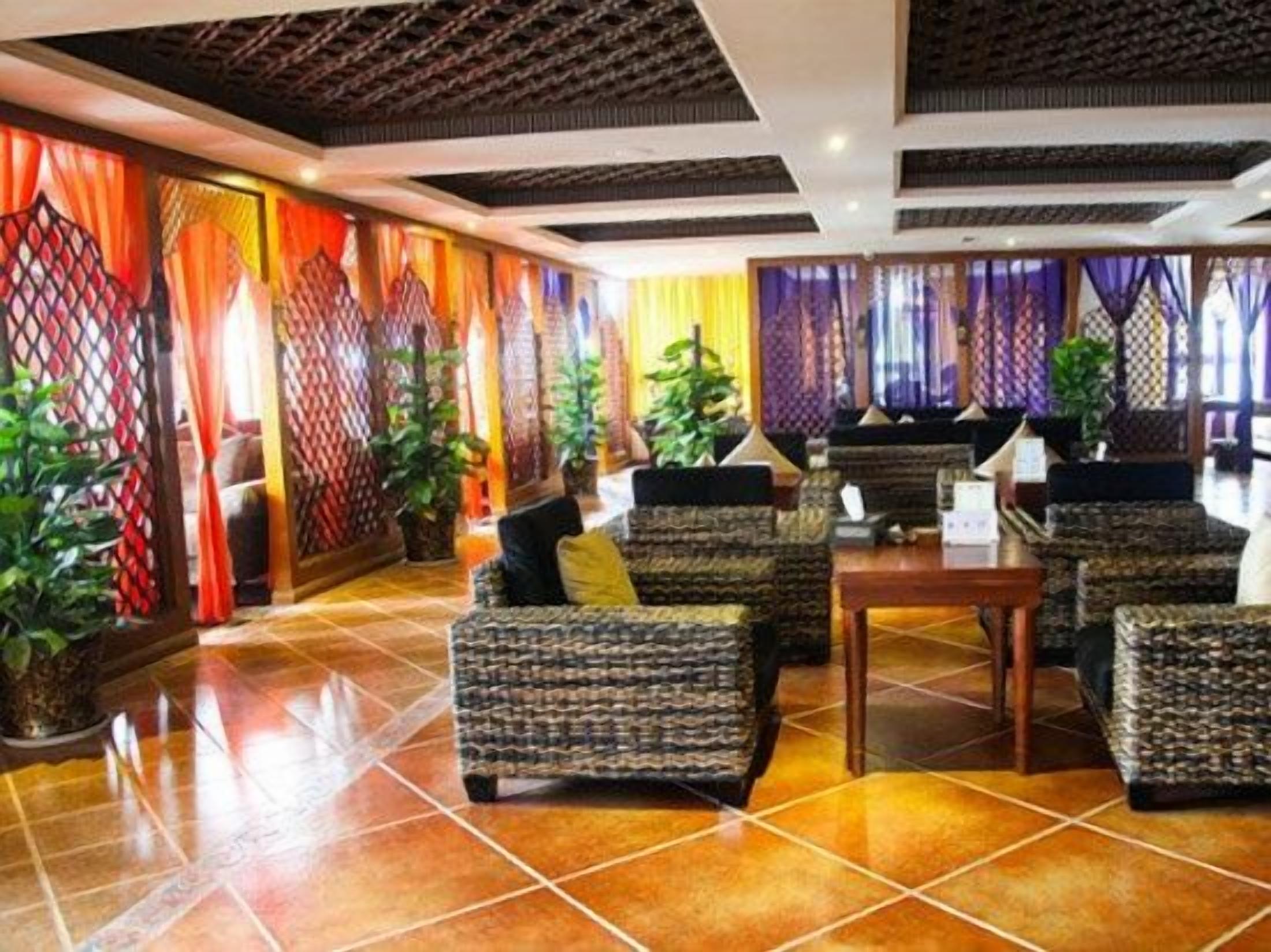 Un vestíbulo con sofás estampados, una mesa de madera y plantas en macetas.
