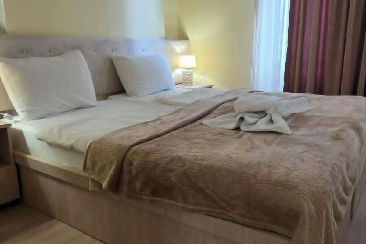 Een hotelkamer met een bed, nachtkastje en lamp.