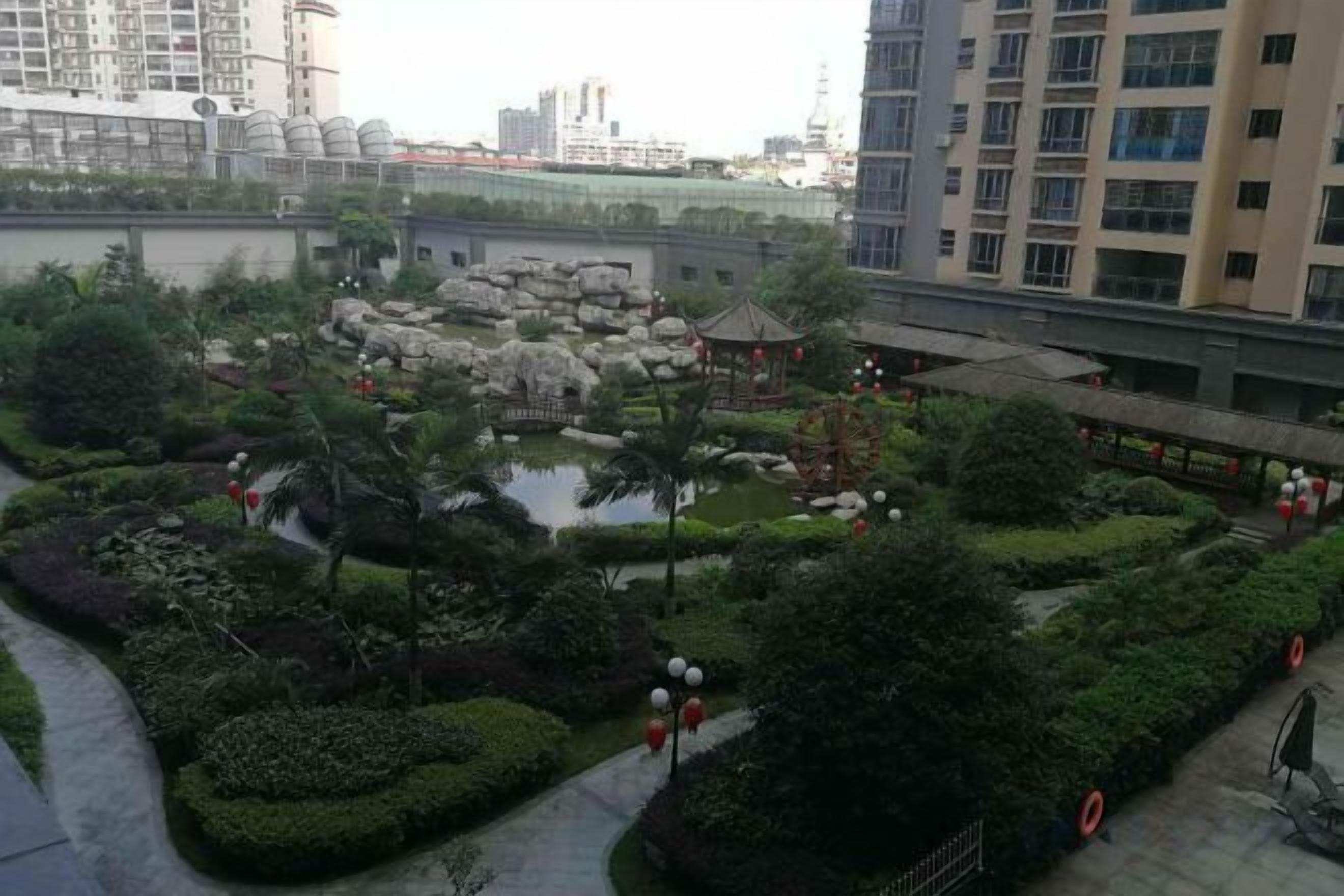 A landscaped courtyard with a pond, rock formations, and a gazebo.