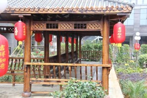A traditional wooden pavilion with a tiled roof, surrounded by greenery and red lanterns. - Huacheng International Hotel (Lechang)