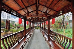 A covered walkway with wooden railings and benches, leading to a building with traditional architecture. - Huacheng International Hotel (Lechang)