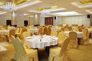 Un salón de banquetes con mesas redondas, sillas y candelabros.