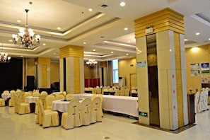 A banquet hall with round tables, chairs, and a chandelier.