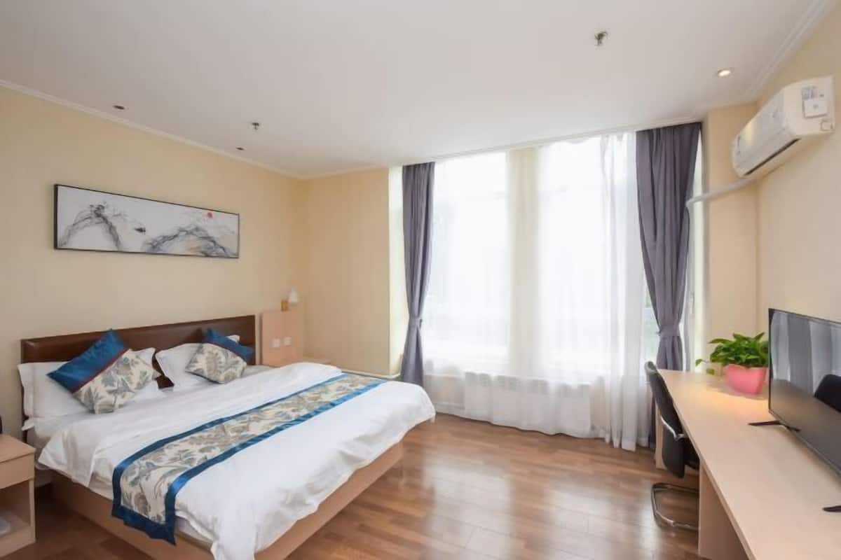 Une chambre d’hôtel avec un lit, un bureau, une télévision et une fenêtre avec des rideaux.