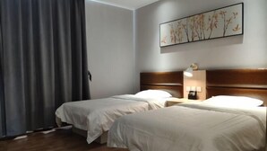 Een hotelkamer met twee bedden, een houten hoofdbord, een nachtkastje met een lamp en een wanddecoratie.