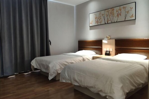 A hotel room with two beds, a wooden headboard, a nightstand with a lamp, and a wall-mounted artwork. - Chenguang Hotel (Shijiazhuang)
