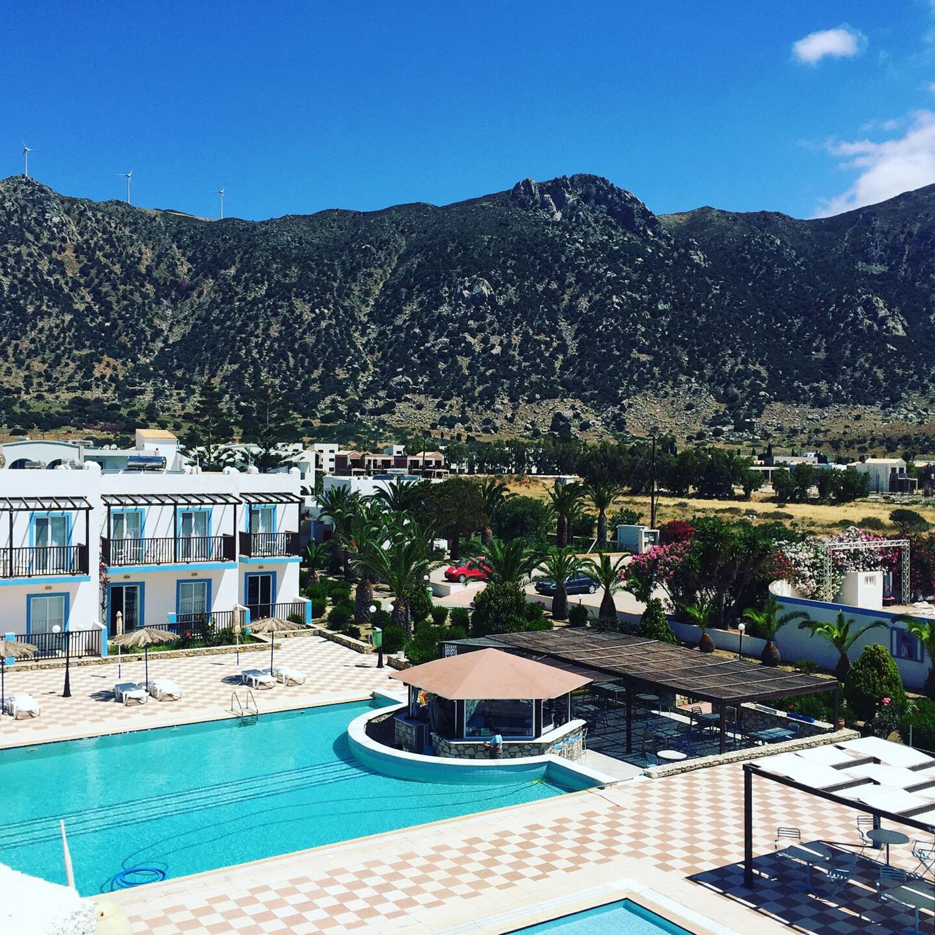 A hotel with a pool, outdoor seating, and a view of mountains.