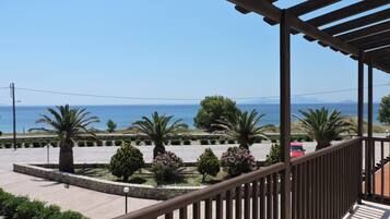 Ein Balkon mit Blick auf das Meer, Palmen und einen Parkplatz.