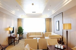 A hotel room with a sofa set, a dining table with cups, a TV, and a lamp. - Shuangyang Hotel (Huairou)