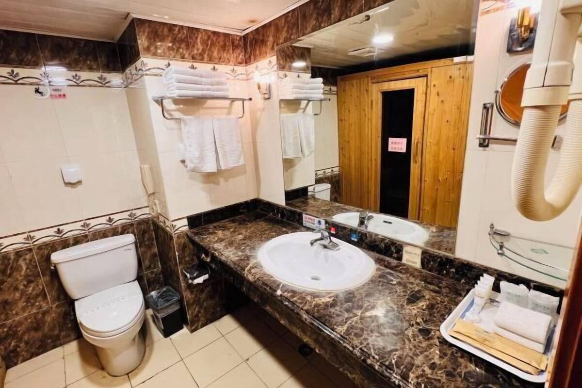 A bathroom with a toilet, sink, and mirror.
