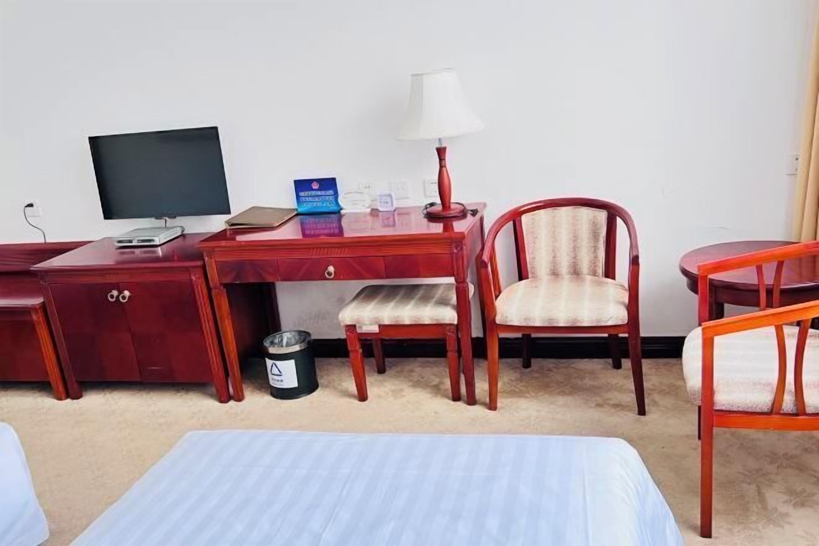 Een hotelkamer met een bureau, een stoel, een bed en een lamp.