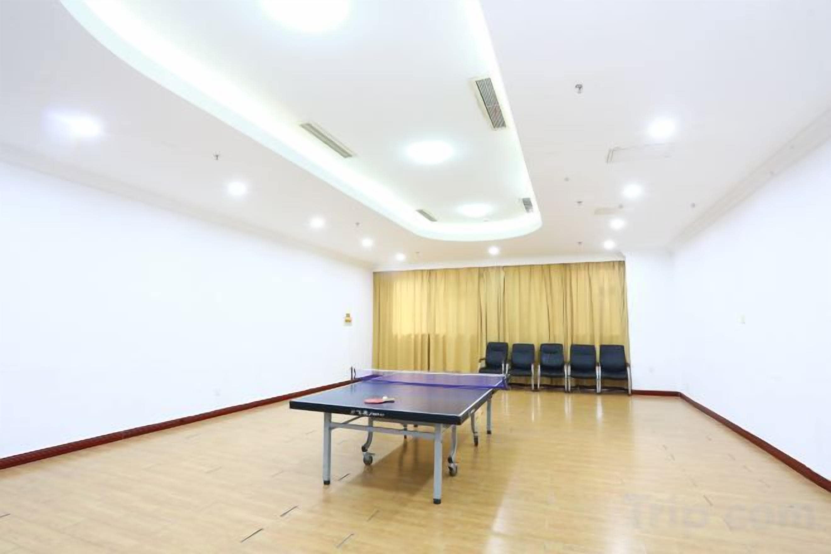 A room with a ping pong table, chairs, and a curtain.
