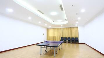 A room with a ping pong table, chairs, and a curtain.