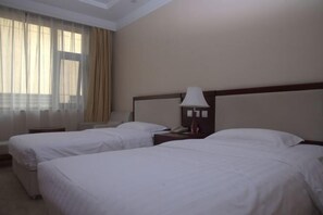 A hotel room with two beds, a nightstand with a lamp, a telephone, and a window with curtains. - Shuangyang Hotel (Huairou)