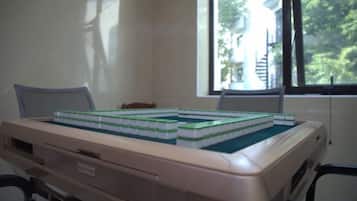 A computer with a chessboard on top, a window with a view of trees, and a chair.