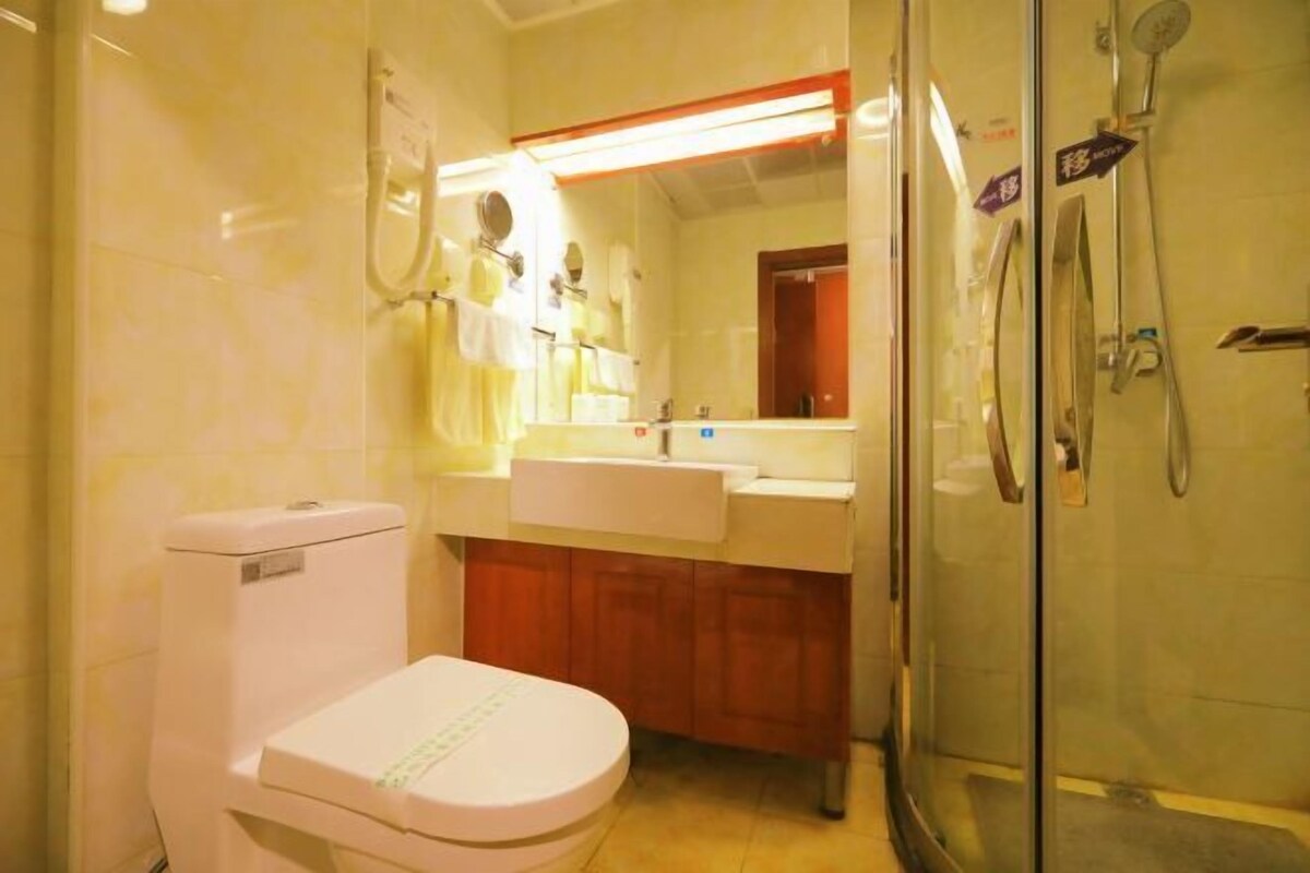 A bathroom with a toilet, sink, mirror, and shower.