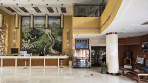 A hotel lobby with a reception desk, a large mural, a staircase, and a seating area. - Shuangyang Hotel (Huairou)