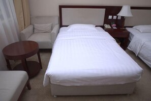 A hotel room with a large bed, a small round table, a sofa, and a nightstand with a lamp. - Shuangyang Hotel (Huairou)