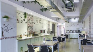 A spacious cafe with tables and chairs, a counter with a menu, and decorative wall art. - Hanting Hotel (Nanjing)