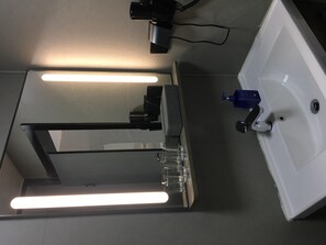 A modern bathroom with a large mirror, a sink, and a toilet. - Hanting Hotel (Nanjing)