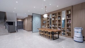 A modern interior with a dining area, bookshelves, and a robotic vacuum cleaner. - Hanting Hotel (Nanjing)